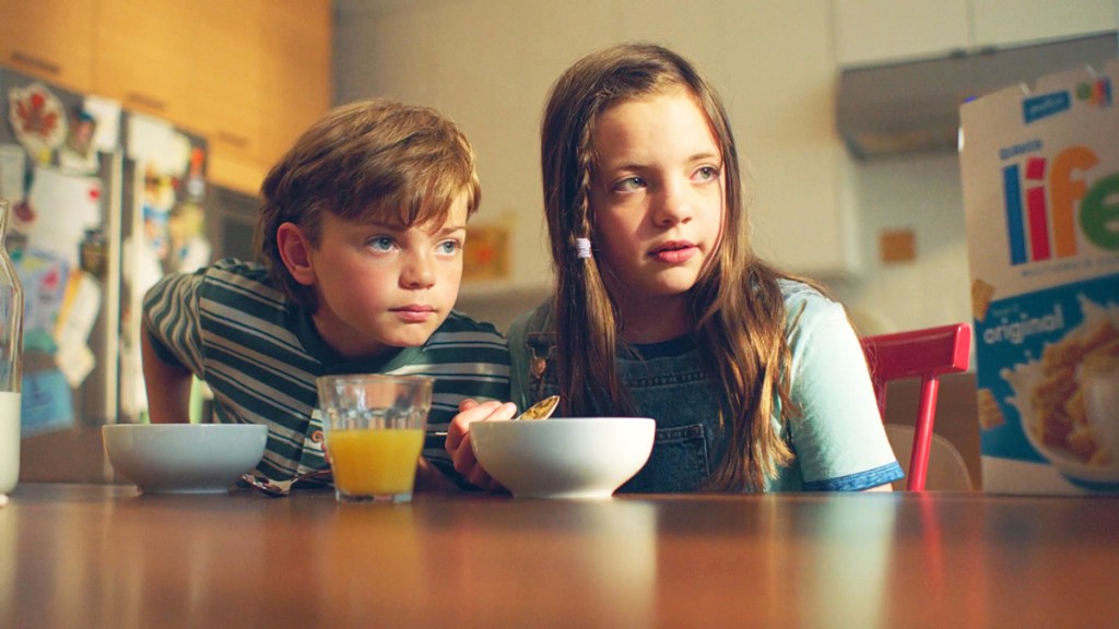 Two children at a kitchen table eating breakfast